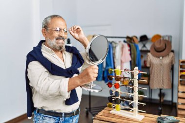 Giysi mağazasında kendine güvenen, kıdemli, gri saçlı bir adam.