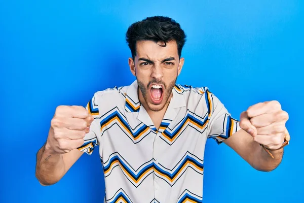 Öfkeli ve kızgın giyinmiş genç İspanyol adam öfkeyle bağırırken kızgın ve öfkeli yumruklar sallıyor. öfke ve agresif konsept. 