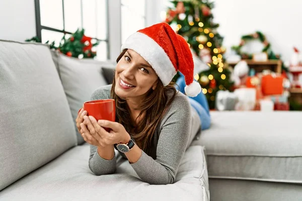 若いですラテン女性飲むコーヒー横によるクリスマスツリーにホーム — ストック写真