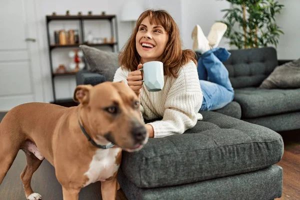 Junge Kaukasierin Trinkt Kaffee Liegend Auf Sofa Mit Hund Hause — Stockfoto