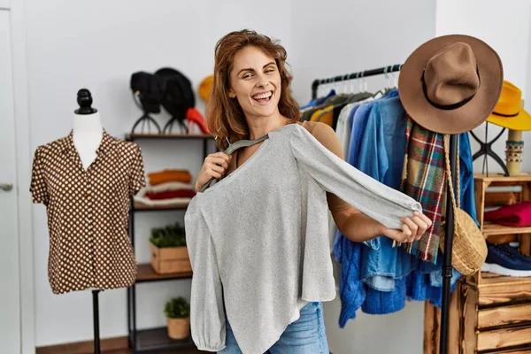 年轻的高加索女性顾客在服装店拿着衣架开心地笑着 — 图库照片