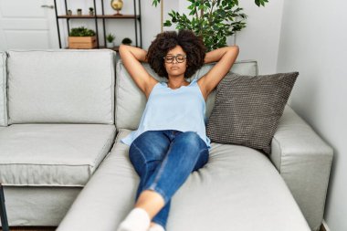 Young african american woman relaxed with hand on head at home