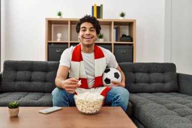 Genç İspanyol adam futbol maçı izliyor ve takımını evde destekliyor..