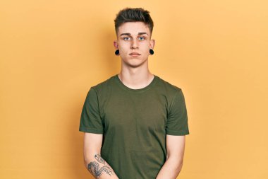 Kulakları genişlemiş, yüzünde ciddi bir ifade olan günlük yeşil tişört giyen beyaz bir çocuk. Basit ve doğal bir şekilde kameraya bakıyorsun.. 