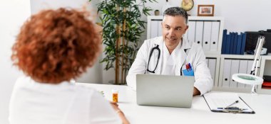 Doktor üniforması giyen orta yaşlı bir adam ve kadın klinikte tıbbi danışmanlık yapıyorlar.