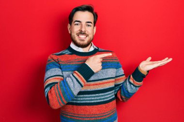 Sakallı, zarif yün kazak giyen yakışıklı beyaz adam kameraya hayret ediyor ve gülümsüyordu.. 