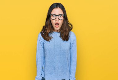 Gündelik kıyafet ve gözlük takan genç ve güzel bir kadın şaşkınlık ve şaşkınlık dolu bir ifade, korku ve heyecan dolu bir yüz.. 