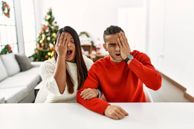 Masada oturan genç latin çift yılbaşı ağacının yanında yarı yüz, göz ve ağız kaplamasından yorgun esniyorlar. Yüzüm acıyor.. 