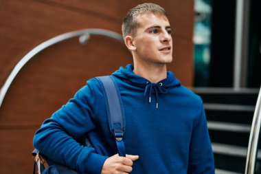 Üniversitede mutlu bir şekilde gülümseyen genç sarışın öğrenci..