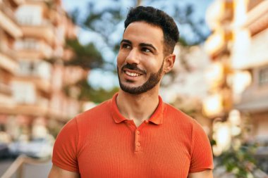 Genç İspanyol adam gülümseyerek şehirde mutlu mesut dikiliyor..