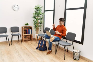 Genç İspanyol adam gülümsüyor. Bekleme odasında kendine güvenen bir video var.