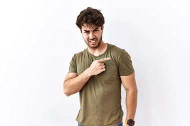 İzole edilmiş beyaz arka planda duran İspanyol adam endişeli ve endişeli bir ifadeye işaret ediyor. 