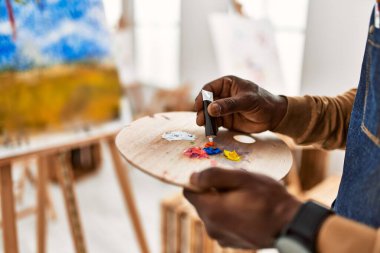 Palet sanat stüdyosunun rengini karıştıran Afrikalı Amerikalı sanatçı..