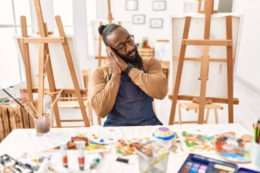 Sanat stüdyosunda uyuyan Afrikalı Amerikalı sanatçı yorgun düşler kuruyor ve elleri ile poz verirken gözleri kapalı gülümsüyor.. 