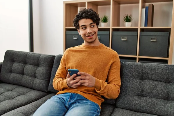 Jonge Spaanse Man Met Smartphone Zittend Bank Thuis — Stockfoto