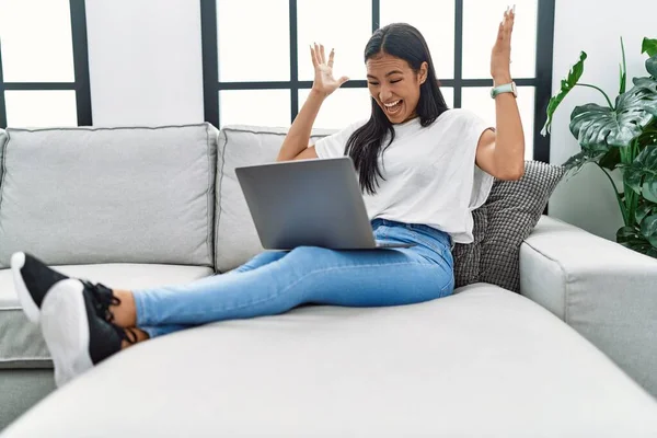 Joven Mujer Hispana Usando Laptop Casa Sentada Sofá Celebrando Victoria —  Fotos de Stock