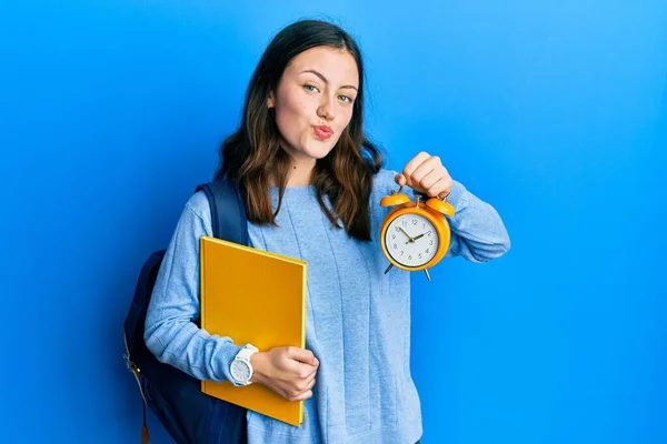 Young Brunette Student Woman Holding Alarm Clock Looking Camera Blowing — Stockfoto