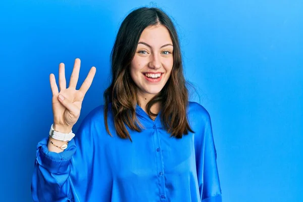 年轻的黑发女人穿着休闲的蓝色衬衫 带着自信和快乐的微笑 用四号手指指指着 — 图库照片