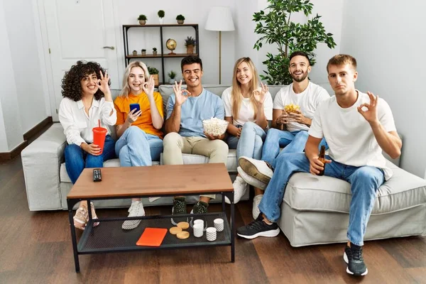 Group People Eating Snack Sitting Sofa Home Doing Sign Fingers — Stockfoto