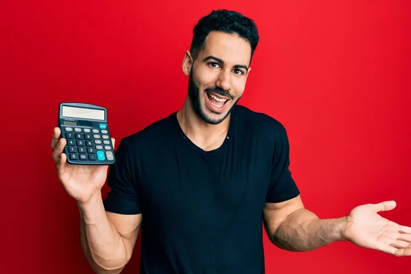 Young Hispanic Man Showing Calculator Device Celebrating Achievement Happy Smile — Stock Photo, Image