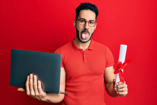 Joven Hombre Hispano Sosteniendo Portátil Diploma Sacando Lengua Feliz Con —  Fotos de Stock