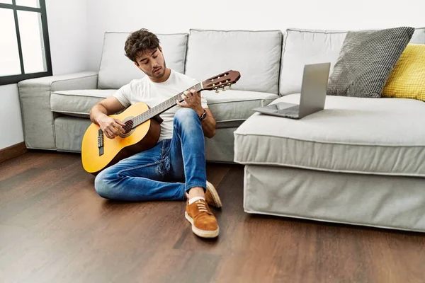 stock image Young hispanic man playing classical guitar at home