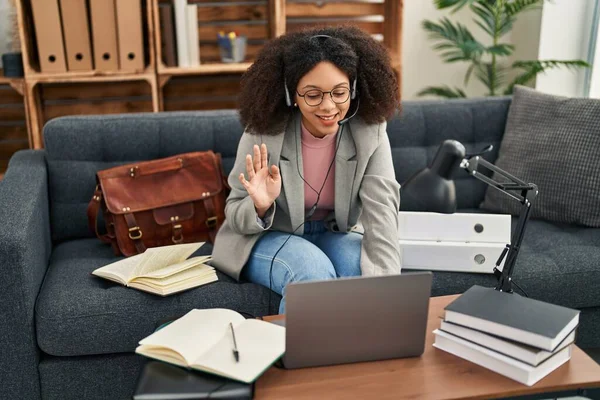 Genç Afrikalı Amerikalı kadın danışma ofisinde online seans yapıyor. Olumlu ve mutlu görünüyor. Kendine güvenen bir gülümsemeyle dişlerini gösteriyor. 