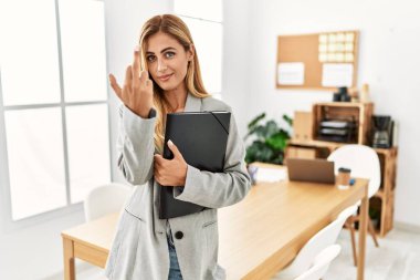Blonde business woman at the office showing middle finger, impolite and rude fuck off expression 