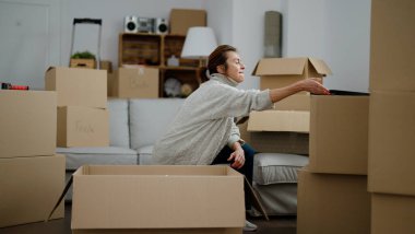 Orta yaşlı İspanyol kadın yeni evinde boks paketini açıyor.