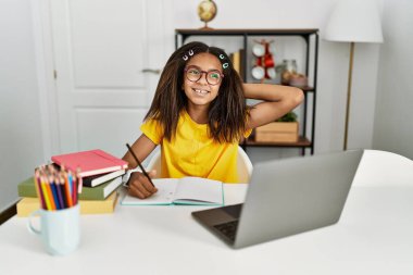 Genç Afrikalı Amerikalı ev ödevi yapıyor. Gülümsüyor, kendine güveniyor, el hareketleriyle saçlara dokunuyor, çekici ve modaya uygun poz veriyor. 