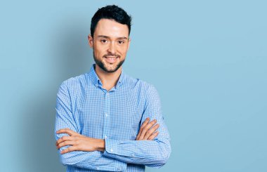 Sıradan iş gömleği giyen, kollarını kavuşturup kameraya gülümseyen İspanyol bir adam. pozitif kişi. 