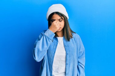 Tatlı yün şapka takan genç Latin kadın yorgun burnu ve gözleri ovuşturup yorgun ve baş ağrısı çekiyor. Stres ve hüsran kavramı. 