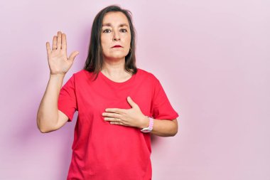 Orta yaşlı İspanyol kadın gündelik giysiler giyip el pençe divan yemin ederek sadakat yemini ediyor. 