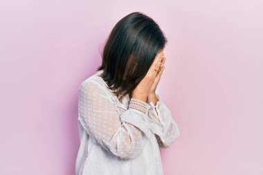 Orta yaşlı İspanyol kadın, günlük kıyafetler giyip ağlarken suratını ellerle kapatıyor. depresyon kavramı. 