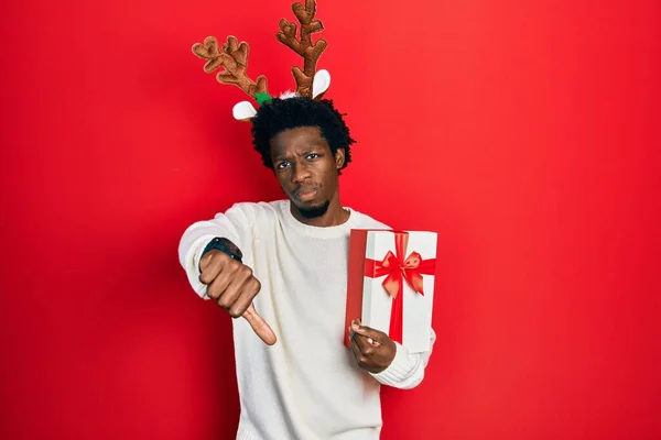 Young African American Man Wearing Deer Christmas Hat Holding Gift — Fotografia de Stock