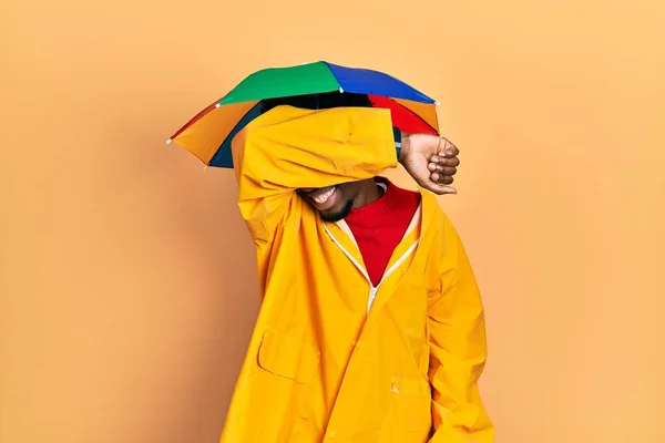 Young African American Man Wearing Yellow Raincoat Covering Eyes Arm — Stock fotografie