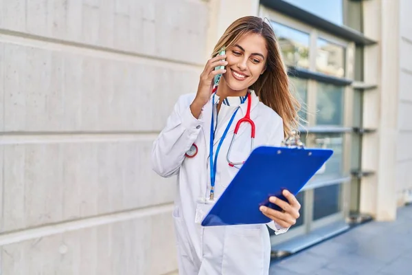 身穿医生制服的金发年轻女子在医院用智能手机交谈 — 图库照片