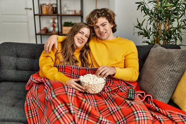 Young caucasian couple watching movie hugging each other at home