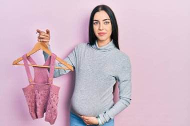 Mavi gözlü güzel bir kadın bebek kıyafetleri bekliyor. Yüzünde ciddi bir ifade var. Basit ve doğal bir şekilde kameraya bakıyorsun.. 