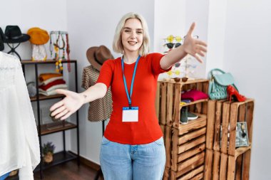 Kafkasyalı genç bir kadın perakende mağazasında yönetici olarak çalışıyor ve kameraya sarılıp gülümsüyor. Mutluluğu kucaklayan neşeli bir ifade.. 