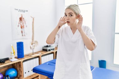 Ağrı kesici kliniğinde çalışan genç beyaz bir kadın iki elini de kulak hareketlerini duymaya çalışıyor. Dedikoduya meraklı. İşitme sorunu, sağır 