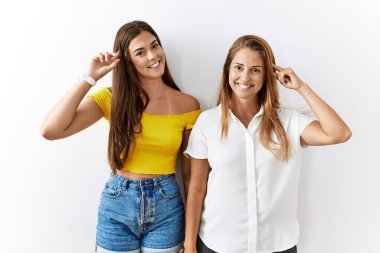 Anne ve kızı yalıtılmış arka planda yan yana durup gülümsüyor ve tek parmakla, harika bir fikir ya da düşünceyle, iyi bir hafızaya işaret ediyor. 