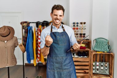 Perakende mağazasının müdürü olarak çalışan yakışıklı genç adam çok mutlu ve heyecanlı bir şekilde kolları havada, gülümseyen ve başarı için bağıran bir jest yapıyor. kutlama konsepti. 
