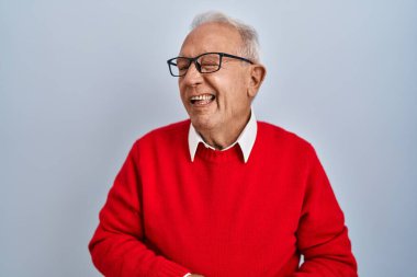 Gri saçlı yaşlı adam izole edilmiş arka planda duruyor. Seksi bir ifadeyle kameraya bakıyor. Neşeli ve mutlu bir yüzü var.. 