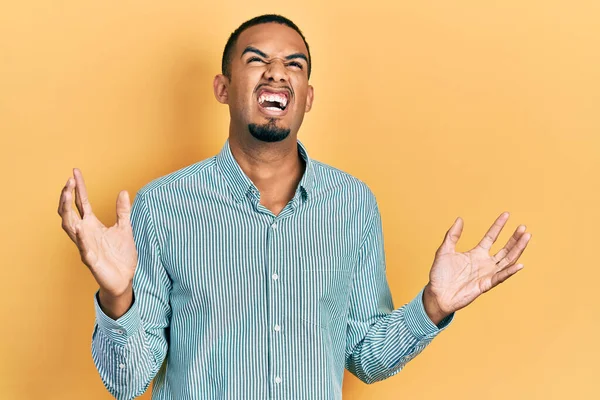 若いアフリカ系アメリカ人の男性は カジュアルな服を着て狂気と怒りの叫びと積極的な表現と腕を上げて叫んでいた フラストレーションコンセプト — ストック写真