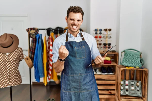 Perakende mağazasının müdürü olarak çalışan yakışıklı genç adam çok mutlu ve heyecanlı bir şekilde kolları havada, gülümseyen ve başarı için bağıran bir jest yapıyor. kutlama konsepti. 