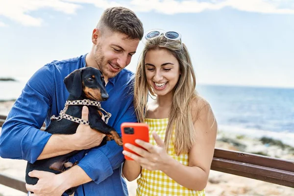 Unga Kaukasiska Par Använder Smartphone Stående Med Hund Stranden — Stockfoto