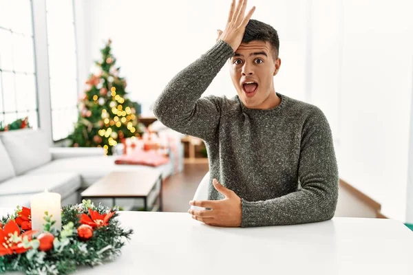 Young Hispanic Man Sitting Table Christmas Tree Surprised Hand Head — 스톡 사진