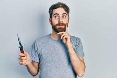 Sakallı, sakallı, ciddi yüzlü, eli çenesinde soru soran beyaz bir adam. Kafa karıştırıcı bir fikir. 