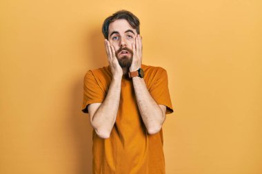 Sakallı, sıradan sarı tişörtlü, yüzü, depresyonu ve üzüntüyü örten beyaz bir adam. 